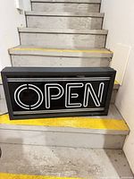 Front view of rectangular OPEN LED lightbox sign on stairs