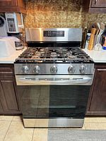 Front view of LG stainless steel gas range showing control panel, burners, oven door and surrounding cabinetry