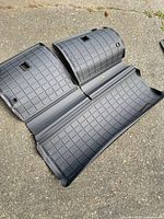 Three-piece black grid-pattern cargo and floor liner set displayed on pavement