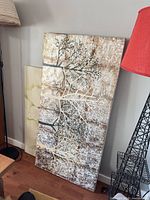 Tree branch canvas and partial floral canvas visible leaning against wall