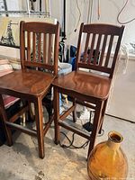 Front view of two matching solid wood slat-back bar stools
