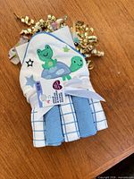 Front view of packaged towel set showing frog and turtle motif and washcloth ends