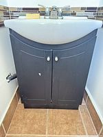 Front view of black cabinet, ceramic basin, chrome faucet and mosaic backsplash