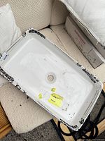 Top view of rectangular white porcelain vessel sink with central drain hole and protective tape