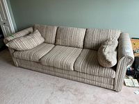 Front view of beige striped three-seat sofa with cushions