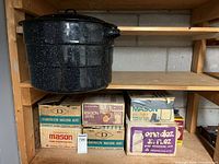 canning pot hanging beside six boxes of Dominion Mason jars on shelf