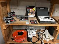 Overall view of shelf with cutter sets, router table box, rotary-tool case, extension cords, power bars and timer module