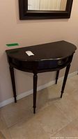 Front view of demilune hall table under wall mirror