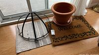 All items together: terracotta pot with saucer, coir doormat, woven rug, metal half-round planter