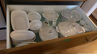 Drawer view showing multiple white CorningWare casseroles, ramekins and spare lids