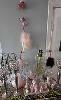 Group shot showing all candlesticks, art glass sculpture, compote, porcelain poodles, flamingo ornaments and pink glass dish
