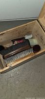 Interior of wooden shoe valet showing brushes, dauber and polish tin