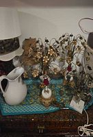 Pitcher, floral brass lamps, candlestick, multiple shades grouped on surface