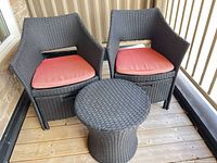 Two armchairs with cushions and small table on wooden deck