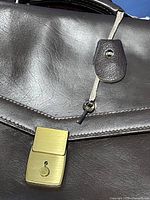Front of brown leather briefcase showing brass lock, key in leather fob