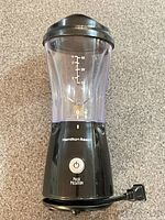 Front view of Hamilton Beach personal blender showing clear cup, measurement markings, pulse button, cord