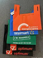 Stack of five reusable shopping bags showing colors, brands and overall condition