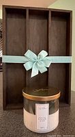 Wood wall shelf cubby with blue ribbon in front, candle with lid