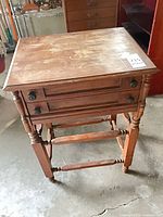 Full view of side table showing drawers, knobs, turned legs, spindle stretchers