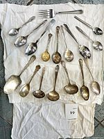 Overview of 17 assorted spoons and serving fork on cloth