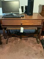 Front view of brown wood veneer desk with keyboard and monitor on top