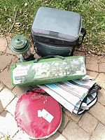All five items together: tent bag, lantern, cooler, KidCo case, striped mat