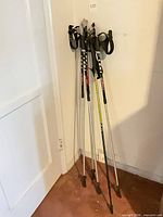 Five Leki trekking poles leaned in corner full view