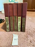 Front view of five maroon slipcases standing upright