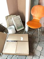 Group view showing orange chair, white coiled light cord and boxes