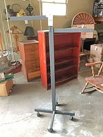 Full view of metal garment rack showing upright, crossbars and caster base