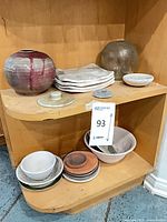 Full shelf with ceramic vase, glass vase, plates, bowls, dishes