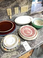 Overview of stacked plates, platters and bowls on countertop