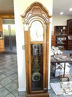 Full frontal view of oak grandfather clock showing overall structure and glass door
