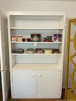 Full front view of white painted wood bookcase cabinet with shelves and lower doors
