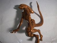 Side view of bronze alien action figure showing full body and tail