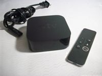 Apple TV unit, Siri Remote, and power cord on flat surface