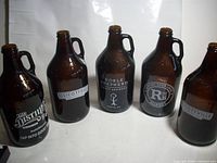 Five amber glass growlers with assorted brewery logos