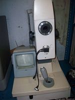 Left side view of Canon CR-DGi camera showing objective lens mount, control base, joystick and CRT monitor