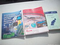 Front covers of three aviation training books laid out on table