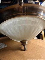 Close view of central frosted glass bowl shade and metal finial