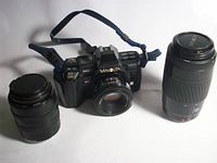 Camera body with attached 50 mm lens flanked by 28–70 mm and 75–300 mm lenses