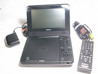Sony portable DVD player open with screen, AC adapter, A/V cable, remote