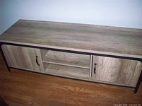 Front view of entire TV stand showing barnwood finish, cabinet doors, shelves, and metal frame.