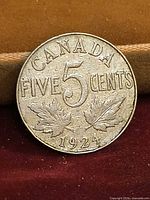 Reverse of 1924 Canadian 5 cent coin showing denomination, maple leaves and date