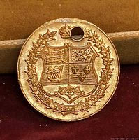 Obverse showing coat of arms, wreath, drilled hole