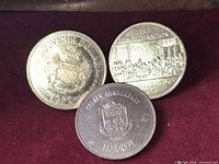 Obverse faces of three trade dollars showing crest, Confederation scene, Golden Anniversary crest