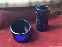 Both cobalt blue glass inserts standing and on side on red fabric