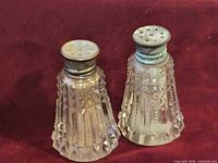 Front view of both shakers showing crystal bodies and tarnished sterling caps
