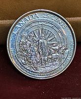 Reverse of coin showing explorers, sled dog and compass design