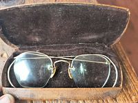 Spectacles in brown leather case, open showing interior velvet lining